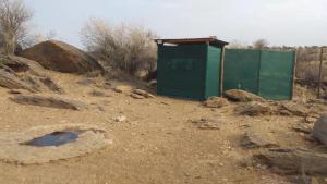 a green shed in the middle of a dirt field at Halala Africa Lodge - Eagle Rock Lodge in Malabar