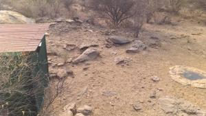 a bunch of rocks in a dirt field with a building at Halala Africa Lodge - Eagle Rock Lodge in Malabar