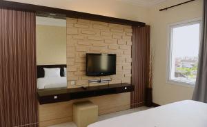 a hotel room with a bed and a tv on a wall at Hotel 88 Jember By WH in Jember
