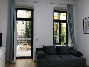 ein Wohnzimmer mit einem Sofa und 2 Fenstern in der Unterkunft Imperial Apartments Schönbrunn - Jadengasse in Wien
