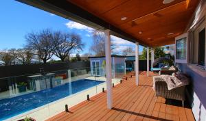 an outdoor deck with a swimming pool on a house at AristaAir- Poppies Luxury Villa in Rotorua