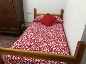a bed with a red pillow on top of it at Casa Antonio Algodonales in Algodonales