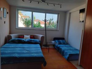 a room with two beds and a couch and a window at Apartman Luce in Trogir