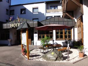 ein Hotel mit einem Tisch und einem Sonnenschirm davor in der Unterkunft Hotel-Restaurant Zum Schwalbennest in Alsfeld