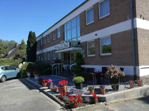 a building with flowers and plants in a parking lot at Hotel Haus am Rieth in Nettetal