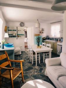 cocina y sala de estar con mesa blanca y sillas en Sifnos Twin Houses, en Apollonia