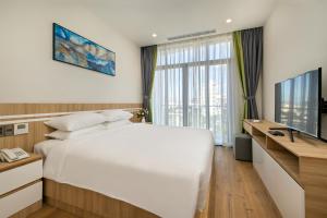 a bedroom with a large white bed and a television at Sun River Hotel & Apartment in Danang