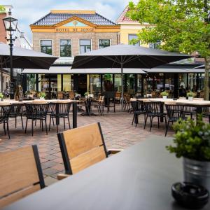 an outdoor patio with tables and chairs and umbrellas at City Hotel de Jonge in Assen