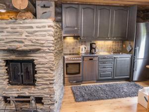 a kitchen with gray cabinets and a stone fireplace at Holiday Home Tortone by Interhome in Ruka