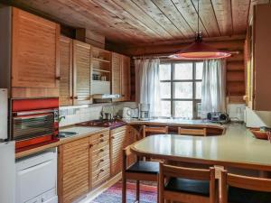 una cocina con armarios de madera y una mesa con sillas. en Holiday Home Revonkanta by Interhome en Kauhaniemi