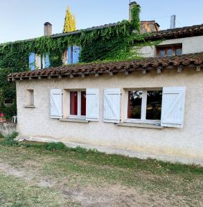 uma casa velha com janelas brancas e hera em La Meyssonnié em Damiatte