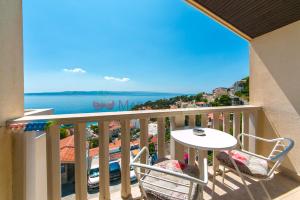 a balcony with a table and chairs and a view of the ocean at Apartments & rooms Merita in Brela