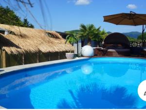 a blue swimming pool with an umbrella and a table at Haus Steffi in Müllheim
