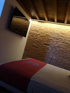een bed in een kamer met een bakstenen muur bij L'Ospitale dei Brilli in Stia