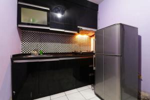 uma cozinha com armários pretos e um frigorífico em Dinda Apartment Tangerang at Apartment Modernland em Kandang-besar