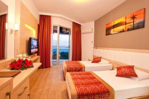 a hotel room with two beds and a television at Gardenia Hotel in Alanya