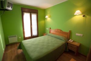 Dormitorio verde con cama y ventana en Pension Monteverde en Cangas de Onís