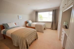 a bedroom with two beds and a window at Long Ledge in Bembridge