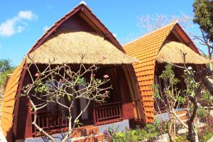 una casa con techo de paja y un árbol en Agasta Villa, en Nusa Penida