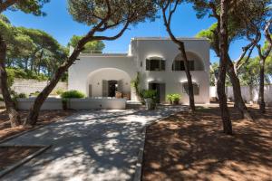 una casa bianca con alberi di fronte di Masseria Villa by Perle di Puglia a Torre Specchia Ruggeri