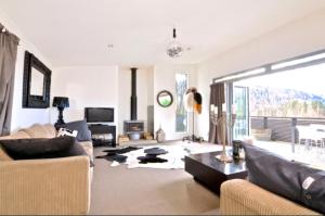 a living room with a couch and a table at Treehouse Spa Escape - Private Spa Pool in Queenstown