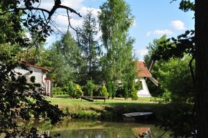 a park with a bench and a house and a pond at Kozi Dwór - Sielanka in Gietrzwałd