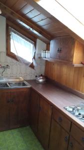 eine Küche mit Holzschränken, einem Waschbecken und einem Fenster in der Unterkunft Mansarda a San Vito di Cadore in San Vito di Cadore