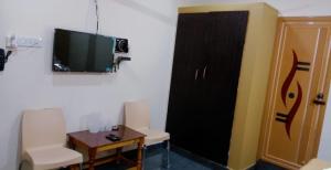 a room with a black door and a table and a tv at Blue Crystal Lodge in Shimoga