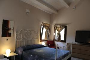 um quarto com uma cama e uma televisão de ecrã plano em Archi Rooms em Loreto