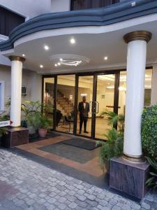 Um homem está na entrada de um edifício. em Citilodge Hotel em Lagos