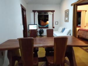 a dining room with a wooden table and a couch at Casa de Temporada in Itaúnas