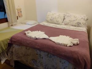 two white towels are sitting on a bed at Casa de Temporada in Itaúnas