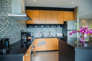 a kitchen with wooden cabinets and a refrigerator at The Woods Natural Park Resort Phuket in Kamala Beach