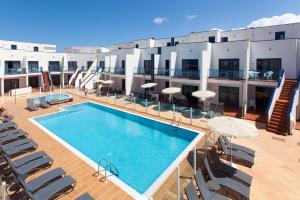 a swimming pool on a building with chairs and umbrellas at TAO El Cotillo in El Cotillo