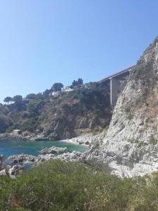 a bridge on the side of a mountain next to a body of water at Appartamento vista mare in Copanello