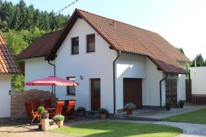 Casa blanca con sillas y sombrilla en Ferienwohnung Nüssleshof, en Fambach