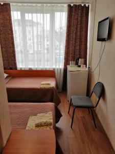コロムナにあるHotel Sovetskayaのベッド2台、椅子、窓が備わる客室です。