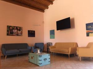 a waiting room with couches and a flat screen tv at Le Sorelle del Vino in Marzamemi