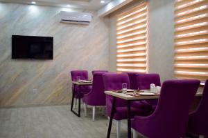 a conference room with purple chairs and a flat screen tv at Dostar Inn in Shymkent