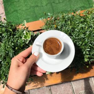 a person holding a cup of coffee on a table at Goji's Apartments in Istanbul