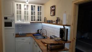cocina con armarios blancos, fregadero y microondas en Ferienwohnung Zirbenduft en Inzell