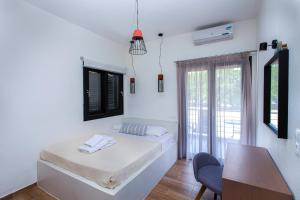 a white room with a bed and a desk and a chair at Kokkinos in Vourvourou