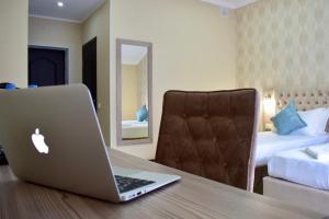 a laptop computer sitting on a wooden table in a hotel room at Dostar Inn in Shymkent +20 photos