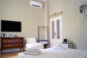 um quarto branco com uma cama, uma cadeira e uma televisão em Ilsanleonardo em Bérgamo