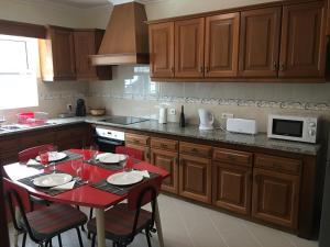 una cocina con mesa roja y sillas. en Casa do Largo, en Furnas