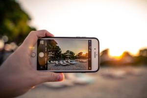 a person taking a picture of a beach with their cell phone at Kokkinos in Vourvourou