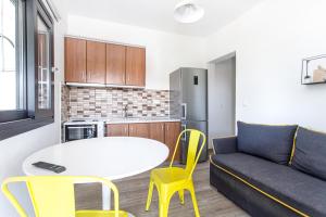 a living room with a couch and a table and yellow chairs at Kokkinos in Vourvourou