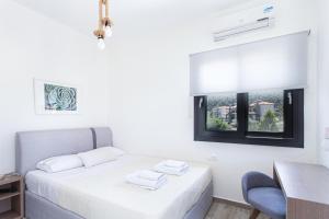 a bedroom with a bed and a desk and a window at Kokkinos in Vourvourou