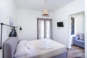 a white bedroom with a bed and a blue couch at Kokkinos in Vourvourou