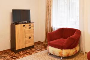 ウラジオストクにある2-х комнатная квартира с 1 спальней в центре городаのリビングルーム(赤い椅子、テレビ付)